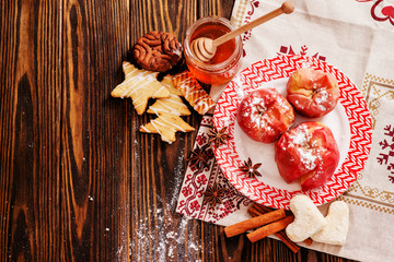 winter dessert , baked apples in powdered sugar , honey , cinnamon , spices and Christmas cookies on a wooden background