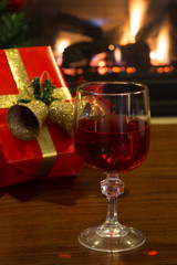 Glass of Red Wine With Christmas Present and Fireplace in Background