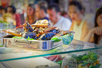 Fototapeta premium Tray on top of lobsters, in blurry background hungry people