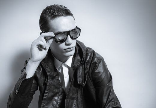 handsome man dressed casual with sun-glasses posing in the studio
