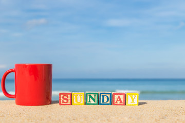 word SUNDAY in colorful alphabet blocks and coffee cup on tropic