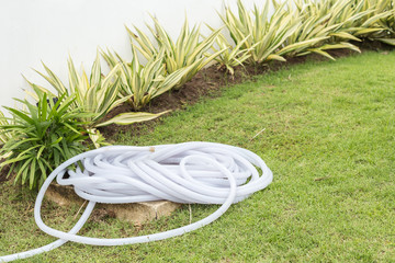 Roll of plastic water hose in the garden