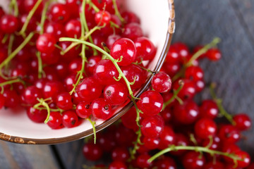 Fresh red currants in bowl on wooden table close up