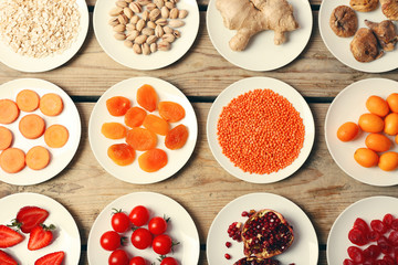 Different products on saucers on wooden table, top view