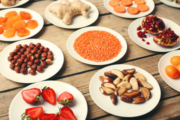 Different products on saucers on wooden table close up