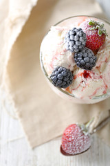 Delicious ice cream with fresh frozen berries, on color wooden background