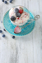 Delicious ice cream with fresh frozen berries, on color wooden background