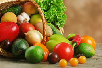Heap of fresh fruits and vegetables in basket on wooden table close up