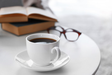 Cup of coffee with books on table in room