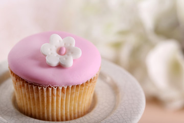 Tasty cupcake on stand, on light background