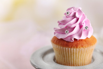 Tasty cupcake on stand, on light background