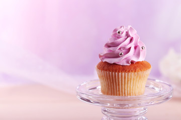 Tasty cupcake on stand, on light background