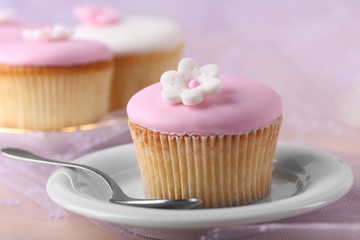 Tasty cupcake on saucer, on light background