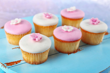Tasty cupcakes on color wooden background