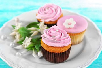 Tasty cupcakes on plate, on color wooden background