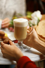 Woman holding cup of latte in cafe