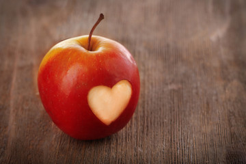 Apple with heart on wooden table
