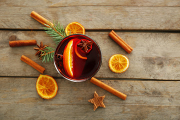 Mulled wine with spices on wooden background