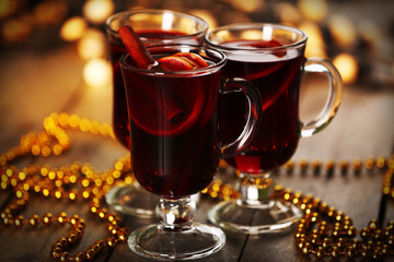 Mulled wine with spices and Christmas tree on wooden background