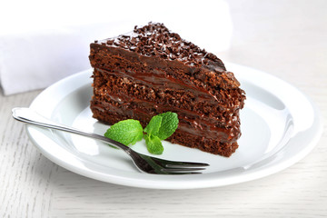 Chocolate cake with chocolate cream on plate, on light background