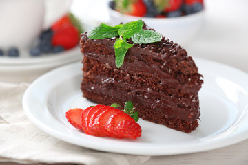 Chocolate cake with chocolate cream and fresh berries on plate, on light background