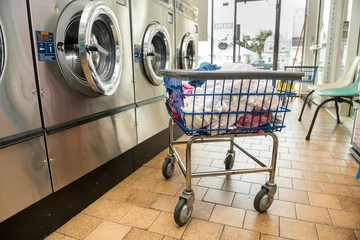 Photo sur Plexiglas Bâtiment industriel Industrial washing machines in a public laundromat, with laundry in a basket