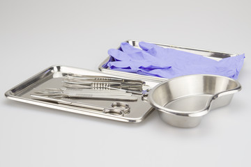 Medical instruments and purple rubber gloves  placed in a tray