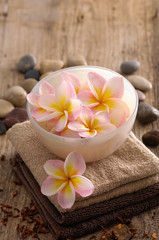 Obraz na płótnie Canvas frangipani in bowl and stones ,dry flower petals ,towel on old wood
