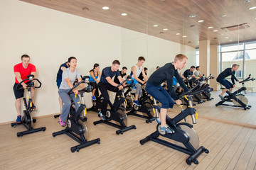 Group of gym people on machines, cycling In Class