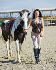 Woman rider with horse walking on hippodrome