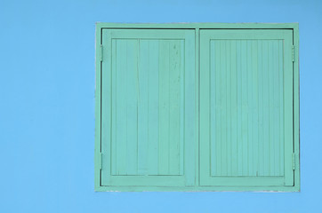 Green wooden window on blue cement wall