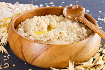 Oatmeal in a wooden bowl and ears of corn oat