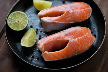 Closeup of uncooked trout steaks with various spices and lime