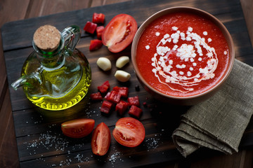 Gazpacho and its ingredients on a rustic wooden cutting board
