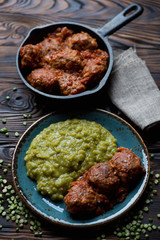 Meatballs in tomato sauce with boiled green peas, studio shot