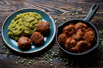 Meatballs in tomato sauce served with green peas, studio shot