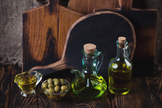 Extra virgin olive oil and green olives, rustic wooden surface