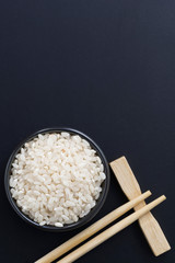 rice and chopsticks for sushi on a black background, vertical
