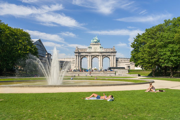 Hot summer in Brussels park of Cinquantenaire with unidentified people enjoying the sun. This monument has been raised to celebrate Belgium's independence