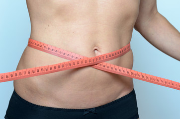 Middle aged woman measuring her waist