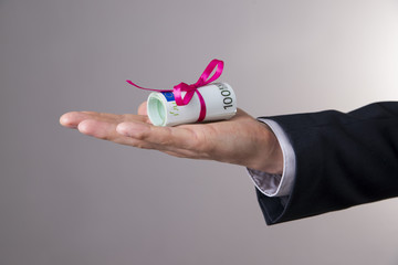 Money with ribbon in male hand on a gray background