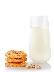 Stack of three homemade peanut butter cookies, peanuts and glass of milk, isolated on white background