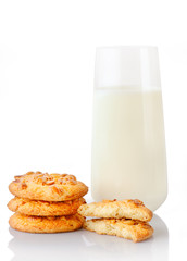 Stack of three homemade peanut butter cookies, halves of cookies and glass of milk, isolated on white background
