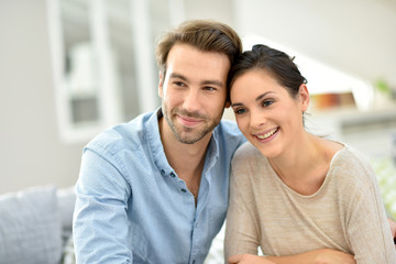 Young smiling couple sitting in sofa at home