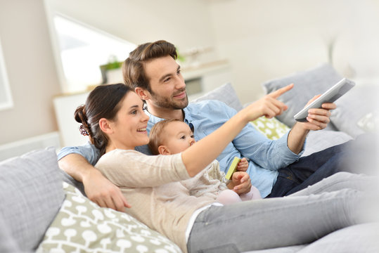 Family with baby in sofa watching tv