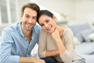 Young smiling couple sitting in sofa at home