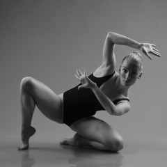 Modern ballet dancer posing on dark background