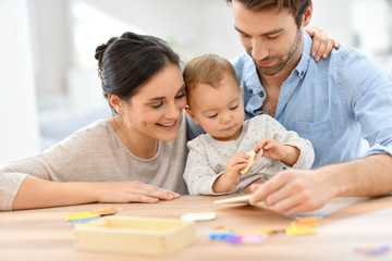 Parents with baby girl playing with wooden game