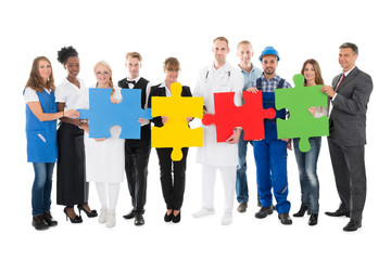 Obraz premium Confident People With Various Occupations Holding Jigsaw Pieces