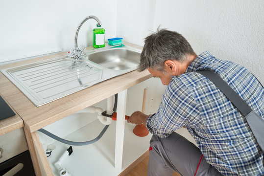 Plumber Fixing Sink Pipe In Kitchen